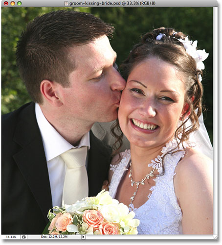 A wedding photo of a groom kissing the smiling bride. Image copyright © 2008 Photoshop Essentials.com
