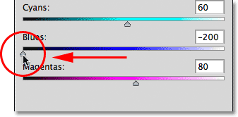 Dragging the Blues slider to the left to darken the sky in the image. Image © 2012 Photoshop Essentials.com